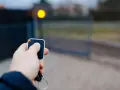 Main tenant utilise une télécommande pour comment programmer une télécommande de portail. Le portail s'ouvre.