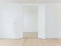 Porte intérieure blanche ouverte, tendance couleur gris clair, sur parquet clair. Un espace minimaliste et lumineux.