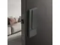 Poignée de porte grise sur fond sombre, avec une serrure silencieuse visible sur le côté.