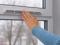 Main tenant ajuste la ventilation d'une fenêtre pour un confort optimal, même par temps froid.