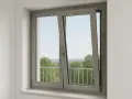 Fenêtre grise avec une ouverture par le haut, laissant entrer la lumière et offrant une vue sur des arbres verdoyants et un ciel bleu.