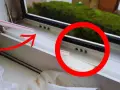 Petite paille rose pointant vers des trous d'évacuation d'eau sur une fenêtre en PVC. Ces trous sont essentiels pour le bon drainage.