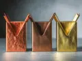 Trois porte-stylos aux formes géométriques, dont un en couleur laiton, sur un fond sombre.