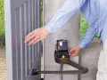 Un homme ajuste le moteur d'un portail électrique bloqué ouvert.