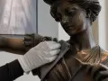 Gant blanc nettoyant délicatement une statue en bronze. Apprenez comment nettoyer bronze pour préserver sa beauté.