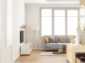 Salon lumineux avec un canapé gris, une table basse et une grande fenêtre ouverture à la française baignant la pièce de lumière naturelle.