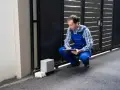 Un technicien vérifie le passage de gaine pour portail coulissant, prenant des notes sur son carnet.