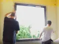 Deux hommes installent une nouvelle fenêtre, une étape clé dans la rénovation de cette pièce.