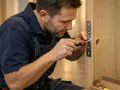 Un serrurier utilise un tournevis pour ajuster une serrure, une étape clé pour savoir comment mesurer un barillet de porte.