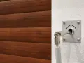Mécanisme pour comment ouvrir une porte de garage électrique de l'extérieur. Un levier est inséré dans une serrure sur un mur blanc, à côté d'une porte en bois.