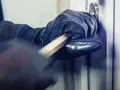 Main gantée utilise un pied-de-biche pour forcer une porte. L'effraction porte ses fruits.