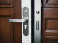 Poignée et serrure argentées sur une porte d'entrée en bois sombre.