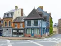 Façades colorées de maisons anciennes, dont une à colombages bleus et blancs. Une description d'une fenêtre ancienne orne la façade orange.