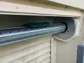 Détail du mécanisme d'un volet roulant, prêt pour comment démonter un moteur de volet roulant. Le tube métallique est visible, avec un support vert.