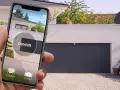 Utilisez votre smartphone pour ouvrir la porte de garage. L'application affiche un bouton "OUVRIR" et des icônes pour le garage et le portail.