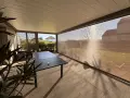 Terrasse avec table et chaises, sous un abri moderne. La menuiserie RAL 7006 s'intègre parfaitement au paysage.