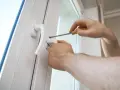 Une poignée de porte vis tourne dans le vide, indiquant un problème de fixation. Un tournevis est utilisé pour tenter de la resserrer.