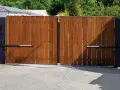 Portail en bois avec motorisation à vérin. Installation discrète pour un accès automatisé.
