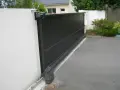 Portail coulissant noir avec son moteur, garantissant la puissance moteur portail coulissant pour une ouverture fluide.