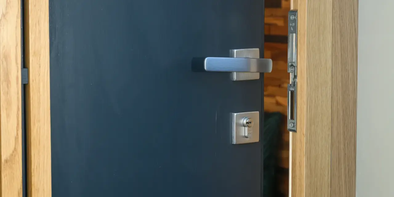 Porte d'entrée moderne bleu foncé avec poignée argentée et serrure. Idéal pour apprendre comment nettoyer des portes en bois.