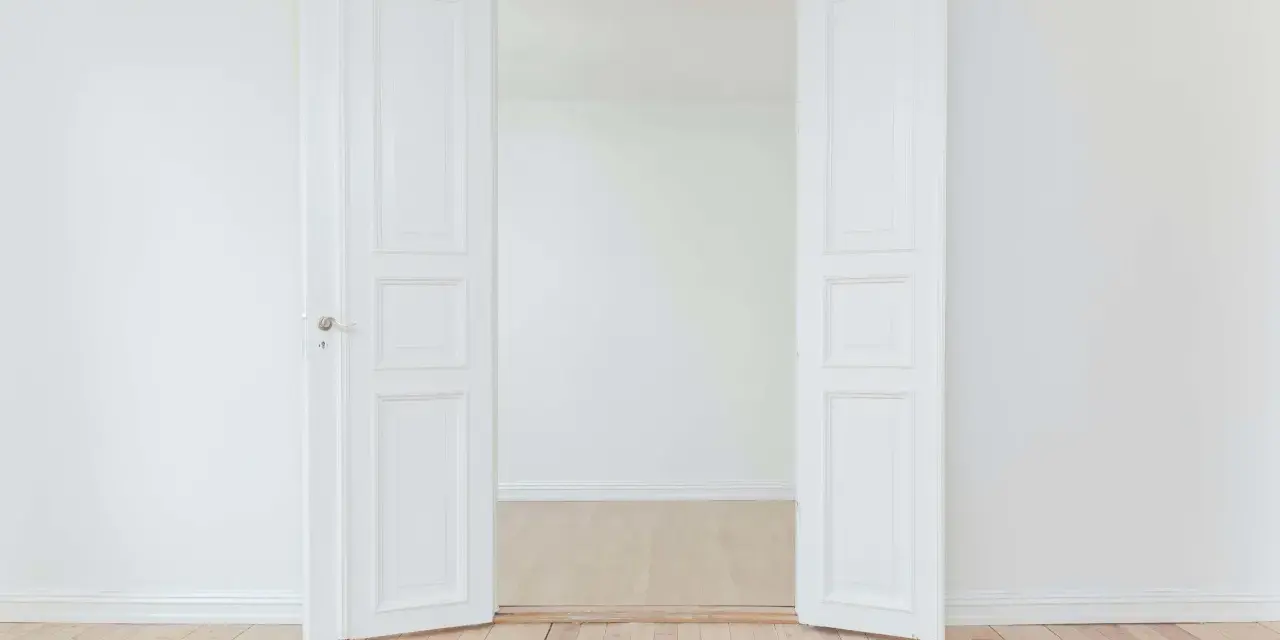 Porte intérieure blanche ouverte, tendance couleur gris clair, sur parquet clair. Un espace minimaliste et lumineux.