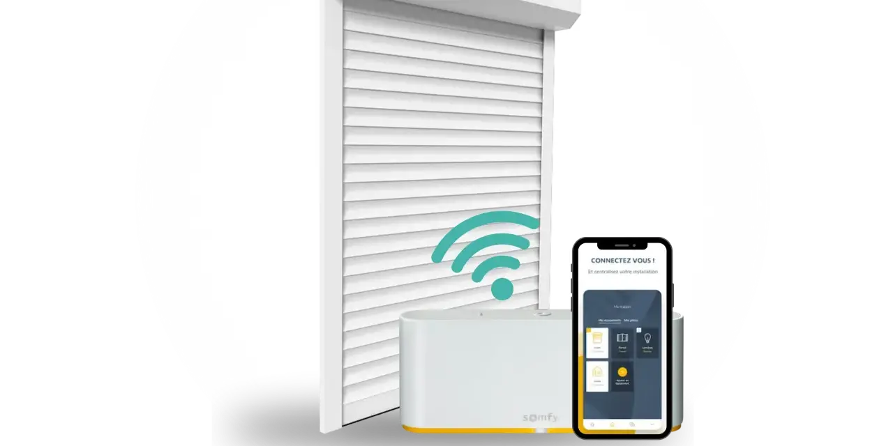 Installation domotique volet roulant : un volet blanc, une box Somfy et un smartphone affichant l'application de contrôle.