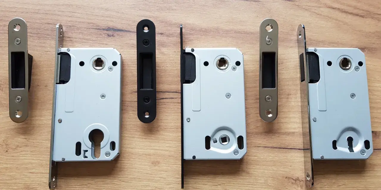 Ensemble de serrures pour porte intérieure, avec leurs gâches argentées et noires, sur fond de bois.