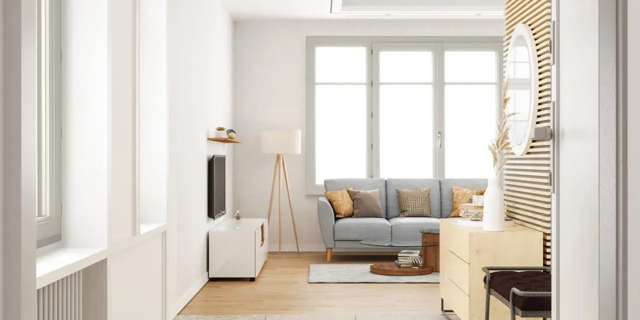Salon lumineux avec un canapé gris, une table basse et une grande fenêtre ouverture à la française baignant la pièce de lumière naturelle.