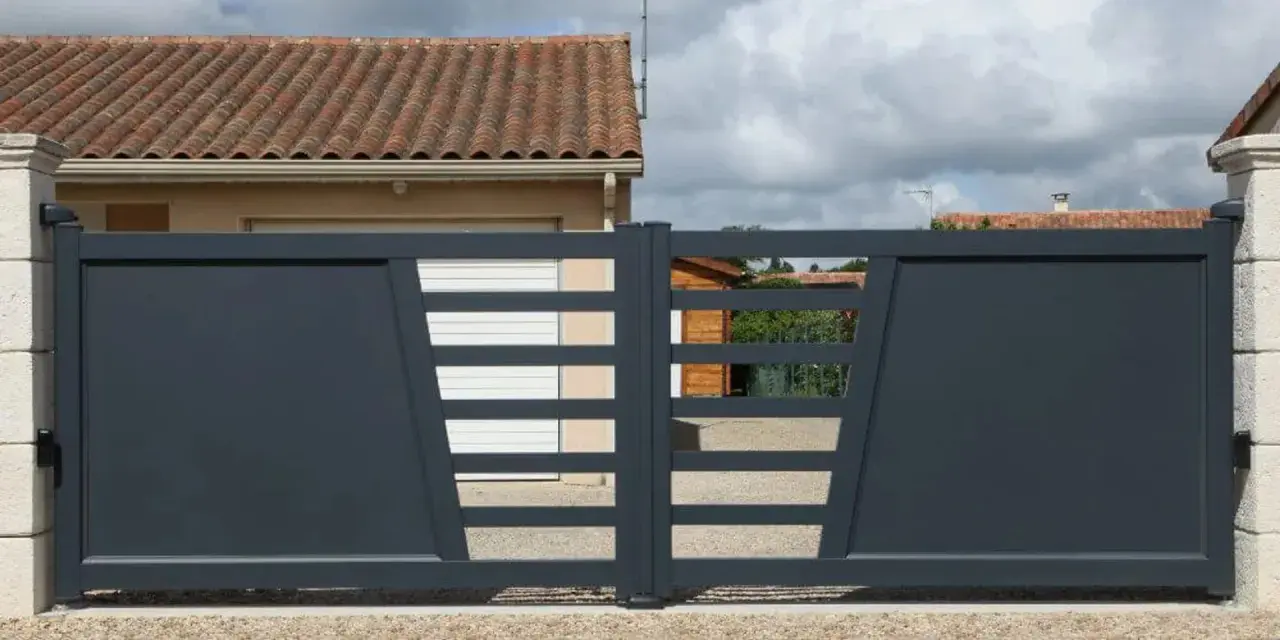 Portail solaire ne fonctionne plus. La grille grise moderne, avec ses lames horizontales et son design asymétrique, est fermée devant une maison.