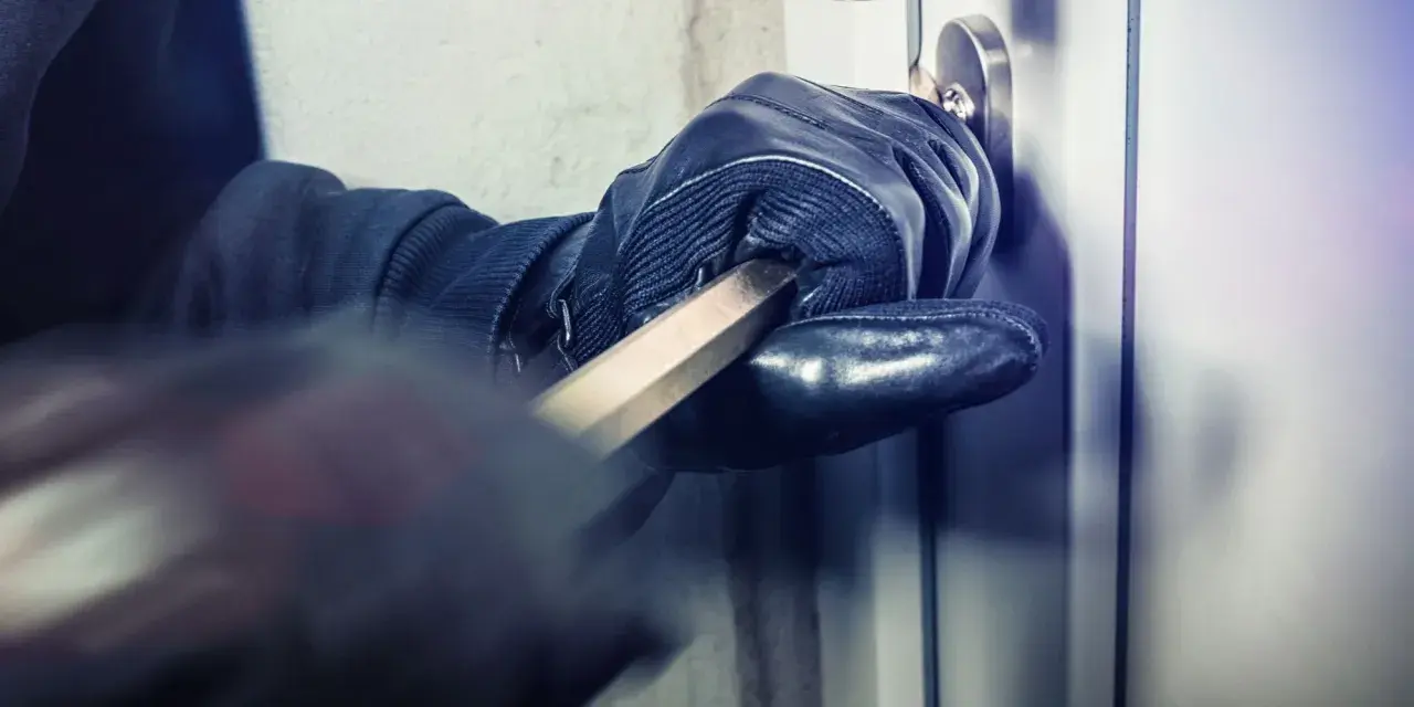 Main gantée utilise un pied-de-biche pour forcer une porte. L'effraction porte ses fruits.