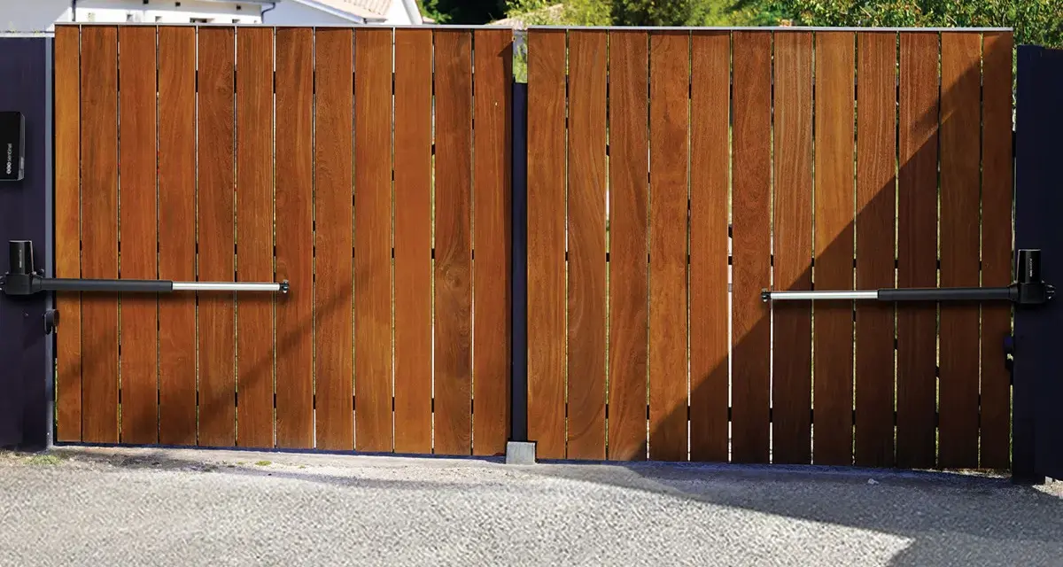 Portail en bois avec motorisation à vérin. Installation discrète pour un accès automatisé.