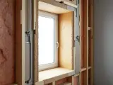 Vue rapprochée d'une fenêtre en cours d'installation, montrant l'isolation et la structure en bois. Idéal pour ceux qui veulent changer fenêtre soi même.