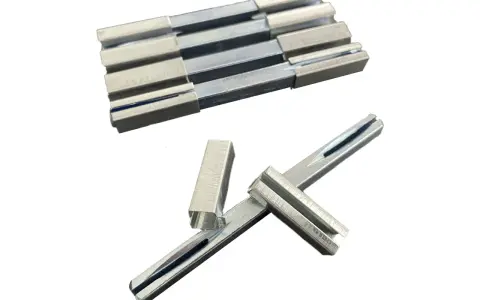 Ensemble de pièces métalliques, dont un carré de serrure, disposées sur fond blanc.