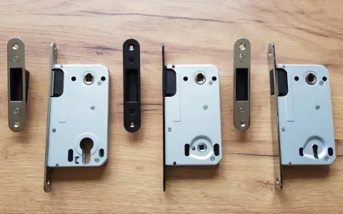 Ensemble de serrures pour porte intérieure, avec leurs gâches argentées et noires, sur fond de bois.