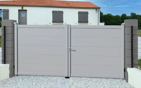 Portail battant gris clair RAL 7035, moderne et discret, s'ouvrant sur une cour pavée devant une maison blanche aux volets gris.