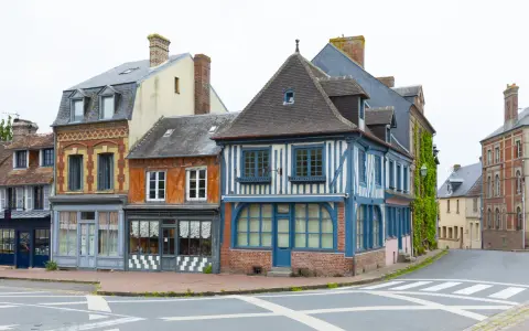 Façades colorées de maisons anciennes, dont une à colombages bleus et blancs. Une description d'une fenêtre ancienne orne la façade orange.