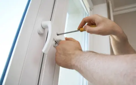 Une poignée de porte vis tourne dans le vide, indiquant un problème de fixation. Un tournevis est utilisé pour tenter de la resserrer.