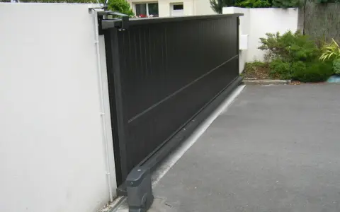 Portail coulissant noir avec son moteur, garantissant la puissance moteur portail coulissant pour une ouverture fluide.