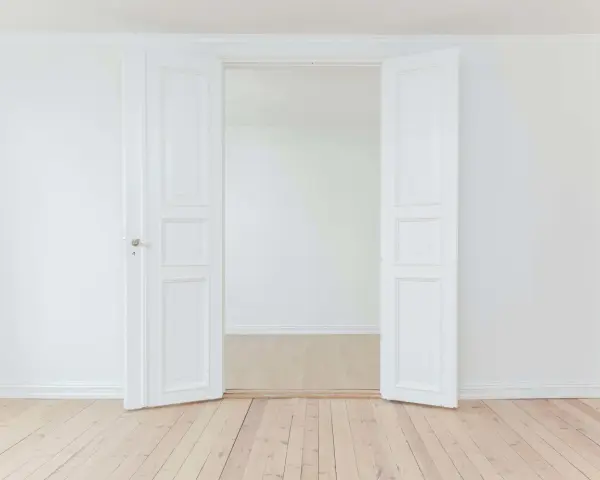 Porte intérieure blanche ouverte, tendance couleur gris clair, sur parquet clair. Un espace minimaliste et lumineux.