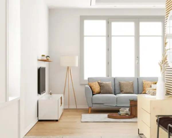 Salon lumineux avec un canapé gris, une table basse et une grande fenêtre ouverture à la française baignant la pièce de lumière naturelle.