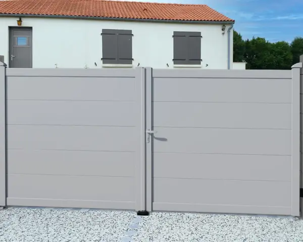 Portail battant gris clair RAL 7035, moderne et discret, s'ouvrant sur une cour pavée devant une maison blanche aux volets gris.