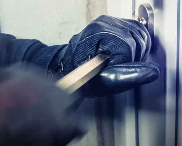 Main gantée utilise un pied-de-biche pour forcer une porte. L'effraction porte ses fruits.