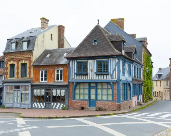 Façades colorées de maisons anciennes, dont une à colombages bleus et blancs. Une description d'une fenêtre ancienne orne la façade orange.