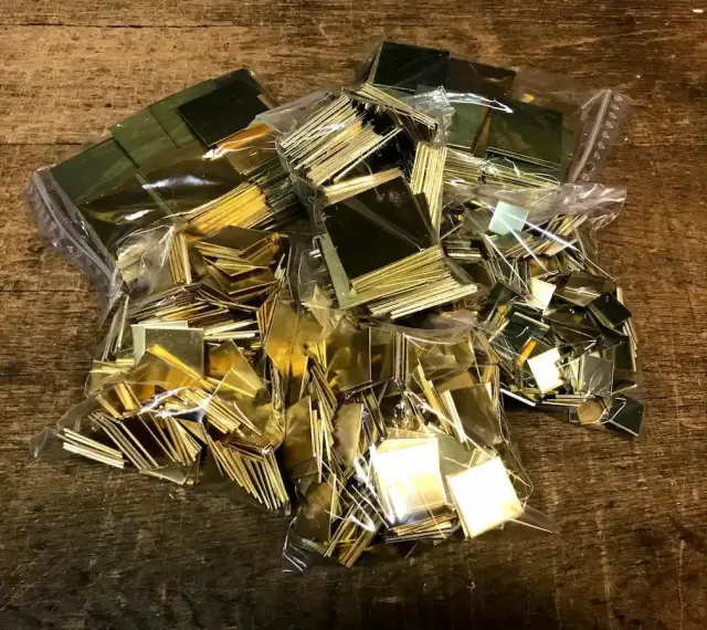 Plusieurs sacs de petits carrés de laiton brillants, prêts pour un projet. Idéal pour apprendre comment nettoyer du laiton.