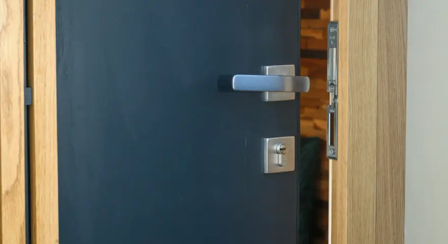 Porte d'entrée moderne bleu foncé avec poignée argentée et serrure. Idéal pour apprendre comment nettoyer des portes en bois.