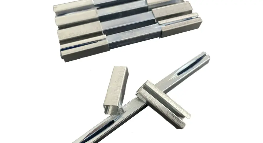 Ensemble de pièces métalliques, dont un carré de serrure, disposées sur fond blanc.