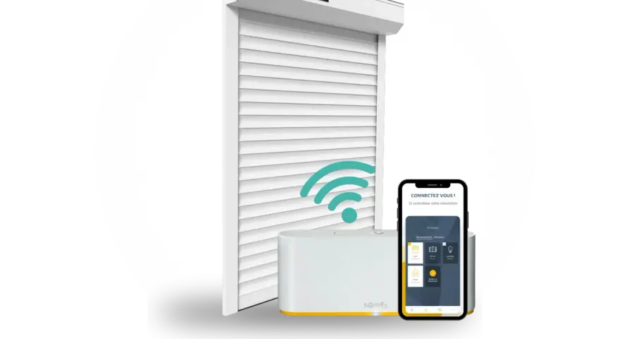 Installation domotique volet roulant : un volet blanc, une box Somfy et un smartphone affichant l'application de contrôle.