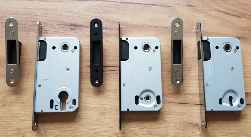 Ensemble de serrures pour porte intérieure, avec leurs gâches argentées et noires, sur fond de bois.