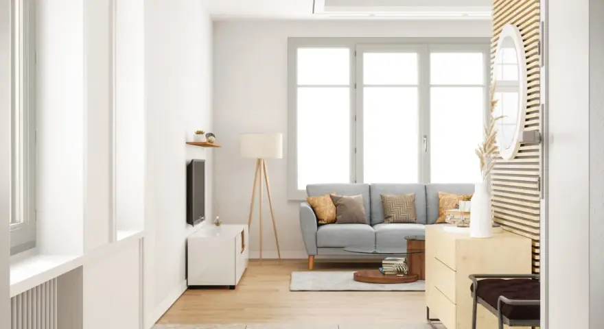 Salon lumineux avec un canapé gris, une table basse et une grande fenêtre ouverture à la française baignant la pièce de lumière naturelle.