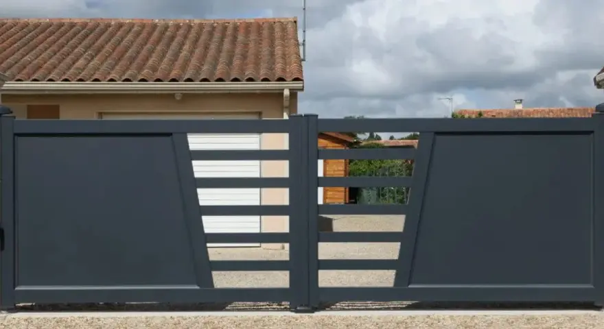Portail solaire ne fonctionne plus. La grille grise moderne, avec ses lames horizontales et son design asymétrique, est fermée devant une maison.